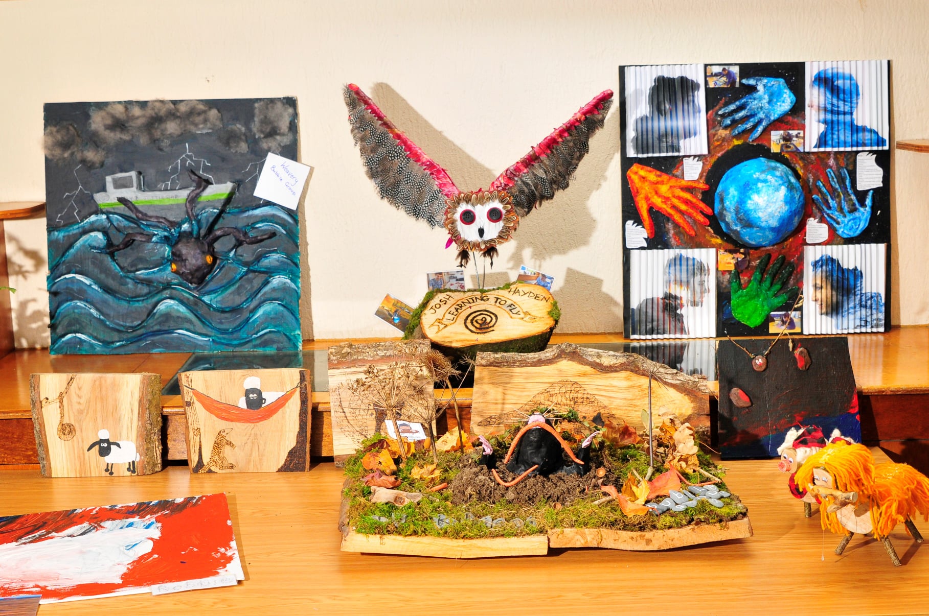 A collection of art including a carved owl and some pictures.