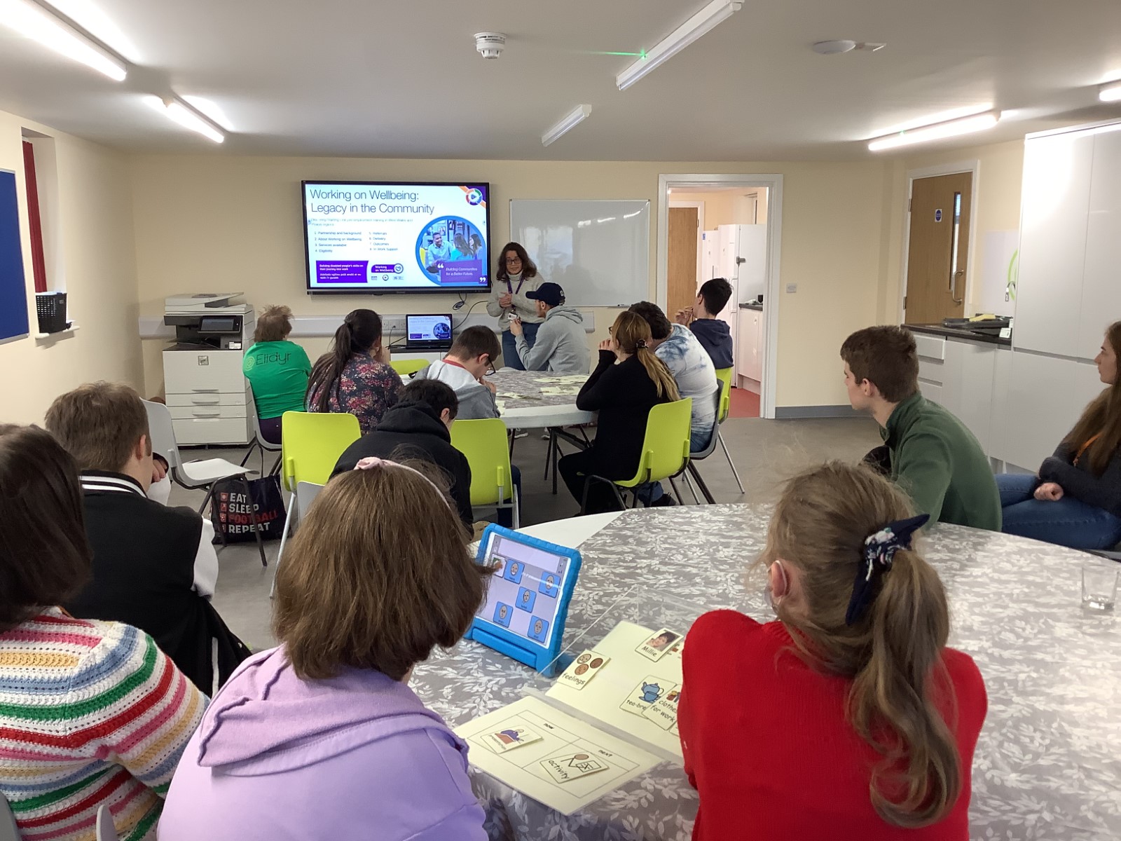 A group of learners in a classroom looking at a presentation on a big screen