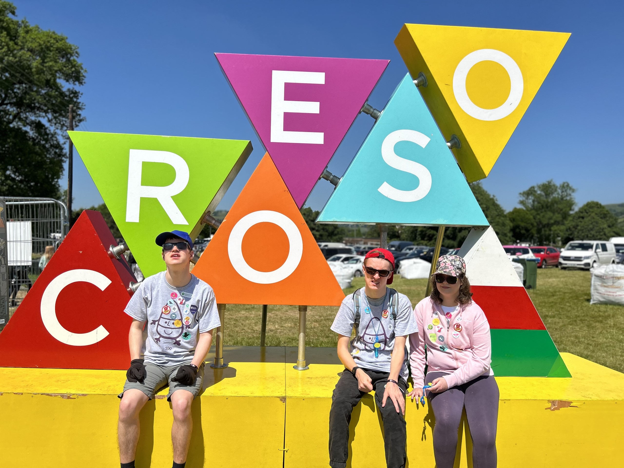 A welcome sign in Welsh - Croeso - Three young people sit under it