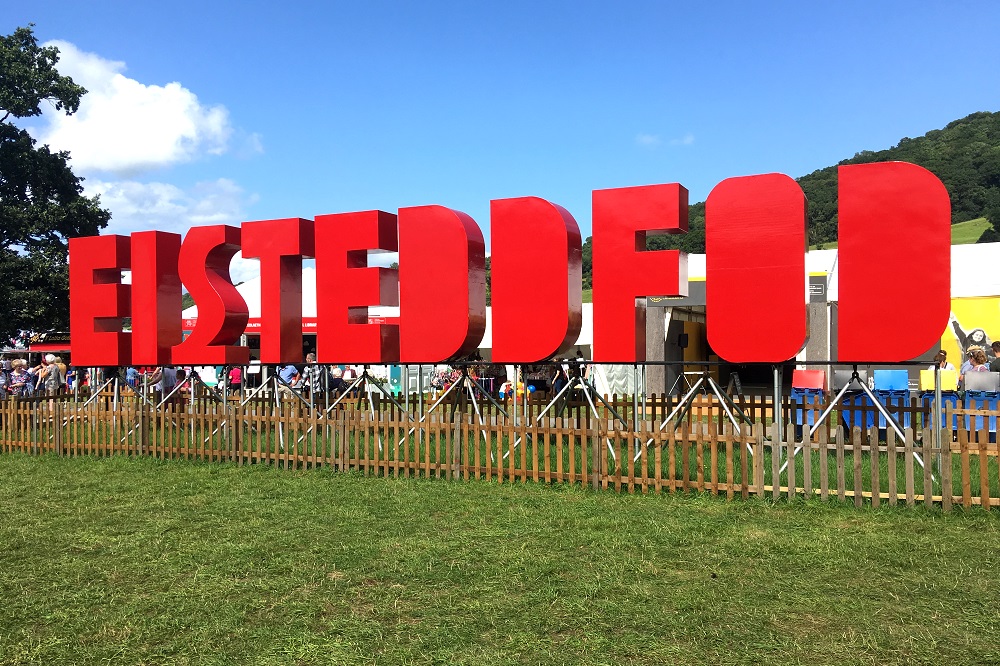 The word EISTEDDFOD in huge red letters in a field in front of a tent.