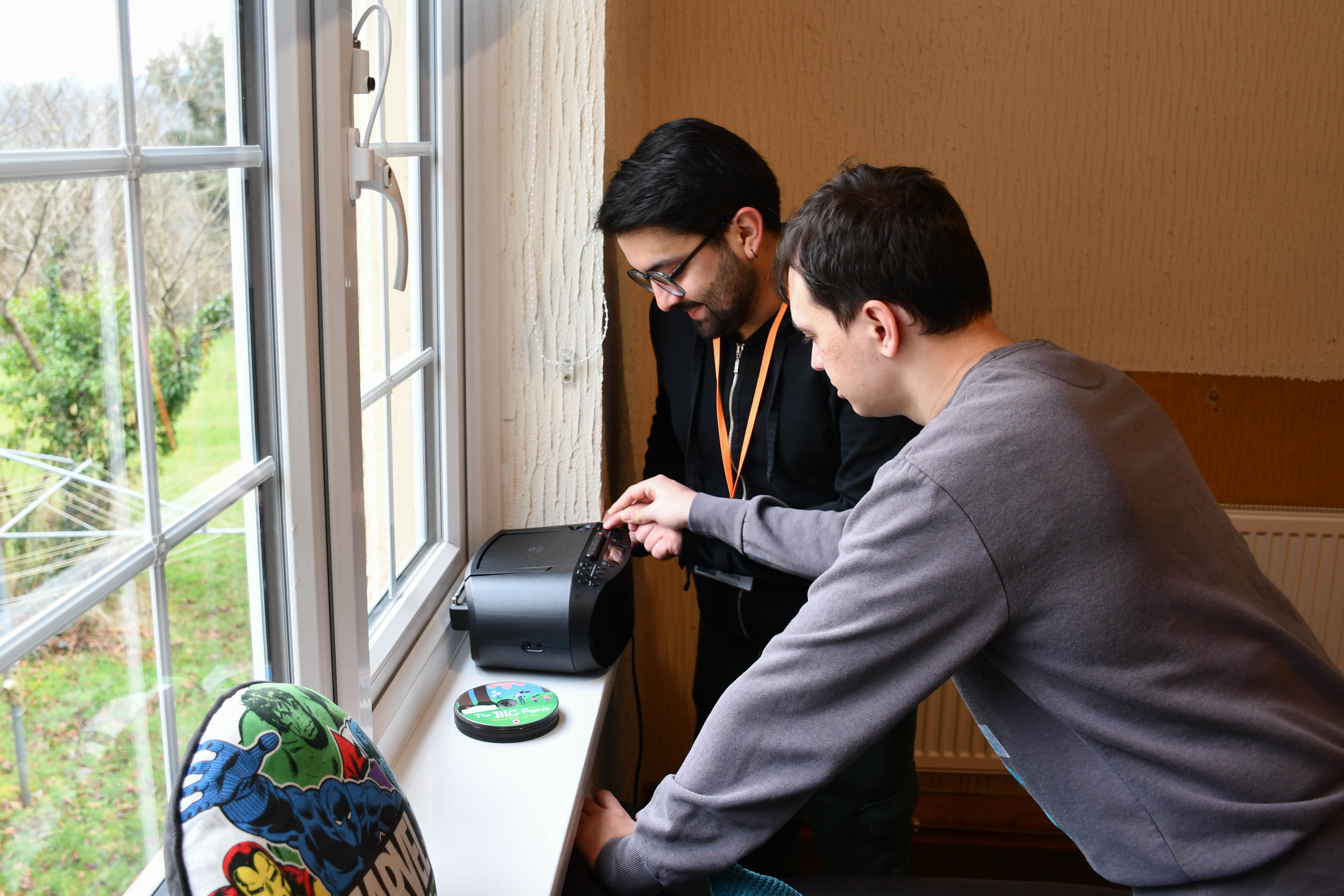 Two men change a CD on a window sill.