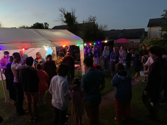 A marquee in a garden at night with lights and people.