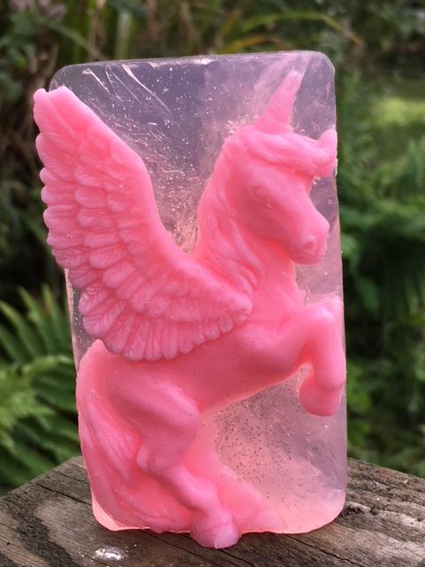 Pink unicorn soap on a plank of wood.