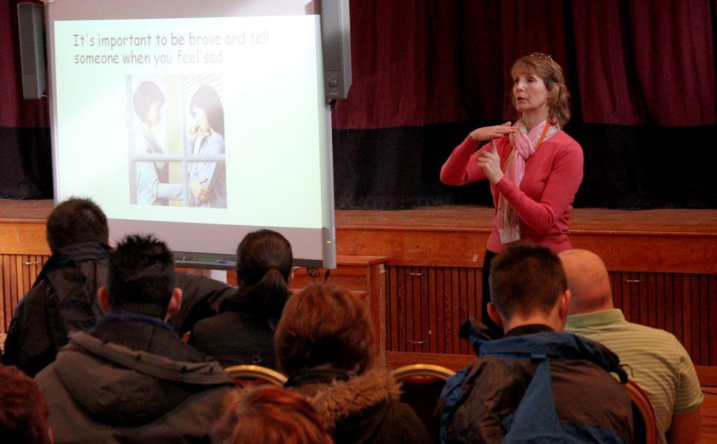 Therapist signing in front of audience.