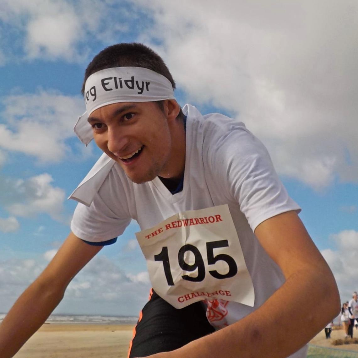 Boy running in a race on a beach in Elidyr headband.