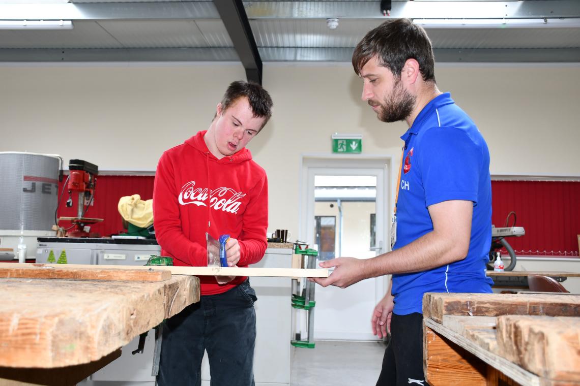 A boy and a tutor work on a piece of woodwork in the education hub 