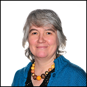 A headshot of a woman with grey hair wearing a blue cardigan.