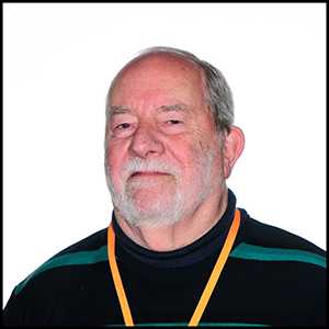 A headshot of a man in a black jumper, wearing an orange lanyard.