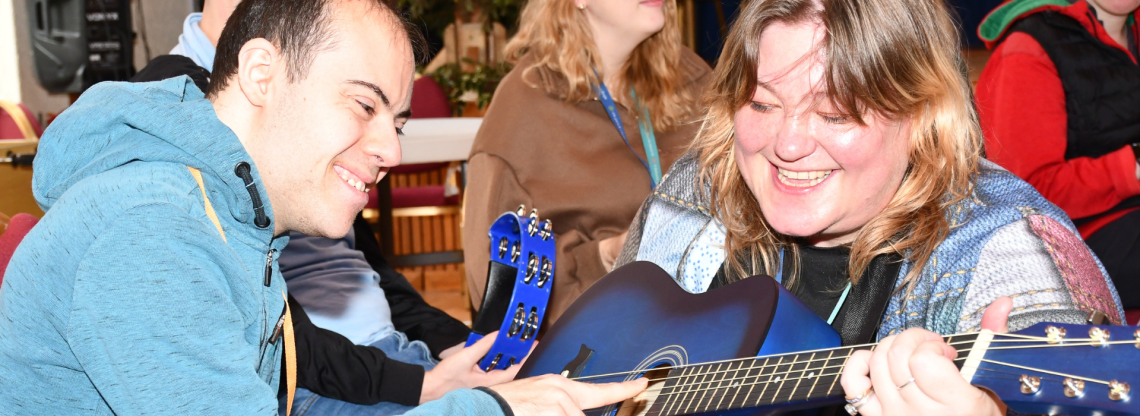 A young man and a woman play a blue guitar 