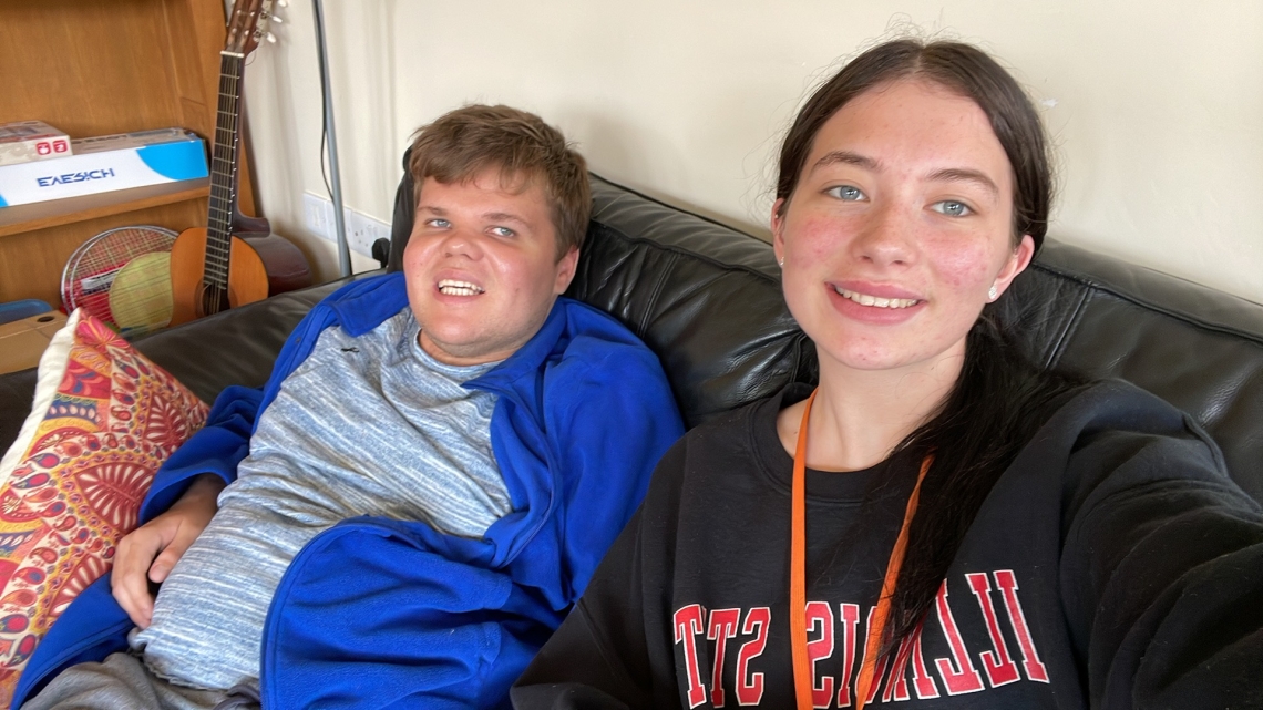 A woman and a young man sit on a sofa in a house