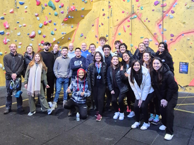 A group of people in a climbing centre stood by a wall.