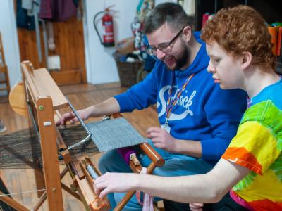 Boy and man at a weaving loom