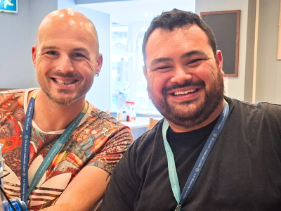 Three men sit at a table and smile.