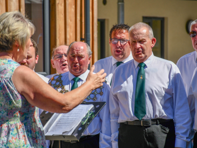 5 men from LLandovery Male Voice Choir sing. There is a woman conducting,