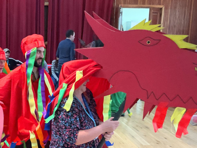 A dragon with a cardboard head with people underneath it