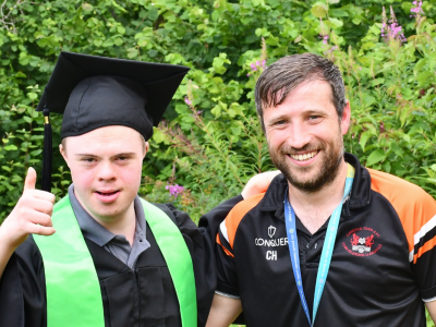A young man in a gown and a tutor. They are outside