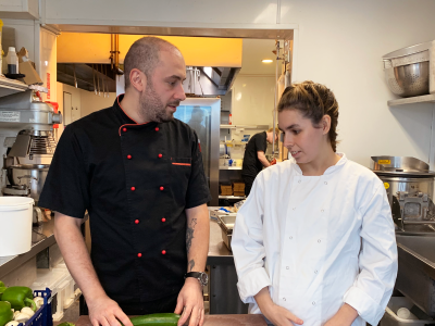 Chef and girl in a kitchen with a courgette.