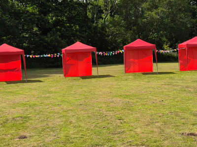 Five red tents on grass with bunting