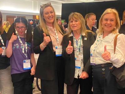 7 conference delegates with lanyards give a thumbs' up