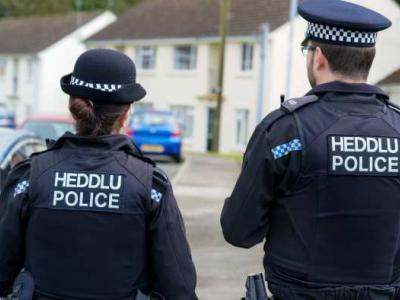 The back of a female and male Welsh police officer from Dyfed Powys police.