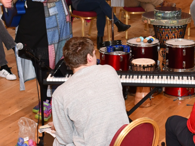 A group playing music in a hall. They sit in a circle.
