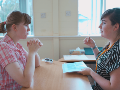 Profile shot of a student and educator sitting at a table talking to each other