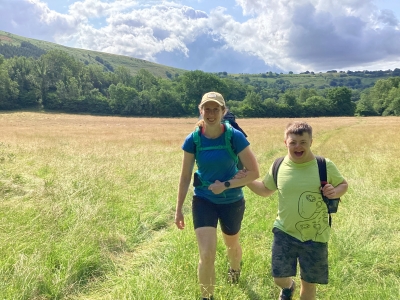 A young woman and a young man on a DofE hike in a field.