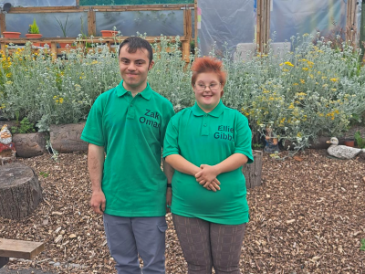 A boy and girl in green t-shirts in a greenhouse for a competition